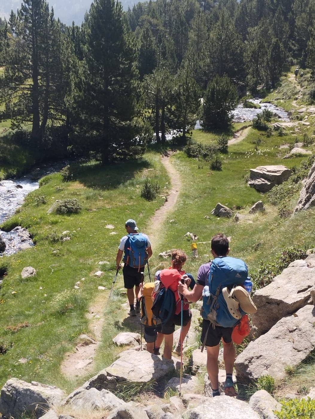 Grupo caminando por un sendero de bosque junto a un río, Carros de Foc